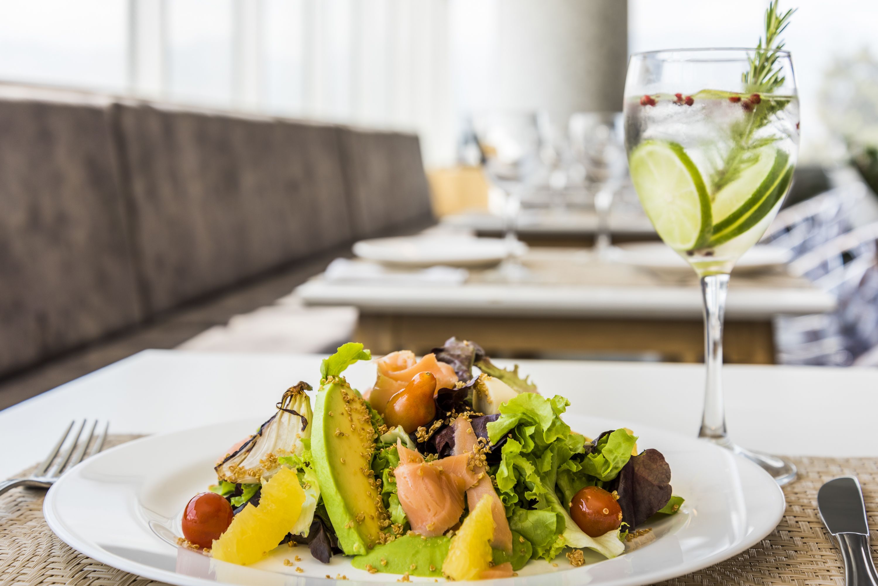 A plate of food with a glass of water and a sprig of rosemary.