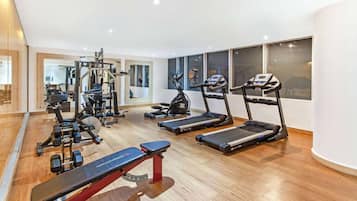 Un gimnasio moderno con diversos equipos de ejercicio, incluyendo cintas de correr, un banco de pesas y máquinas de musculación.
