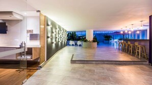 A modern hotel lobby with a reception desk, seating area, and a view of the outdoors. - La Quinta by Wyndham Medellin (Medellín)