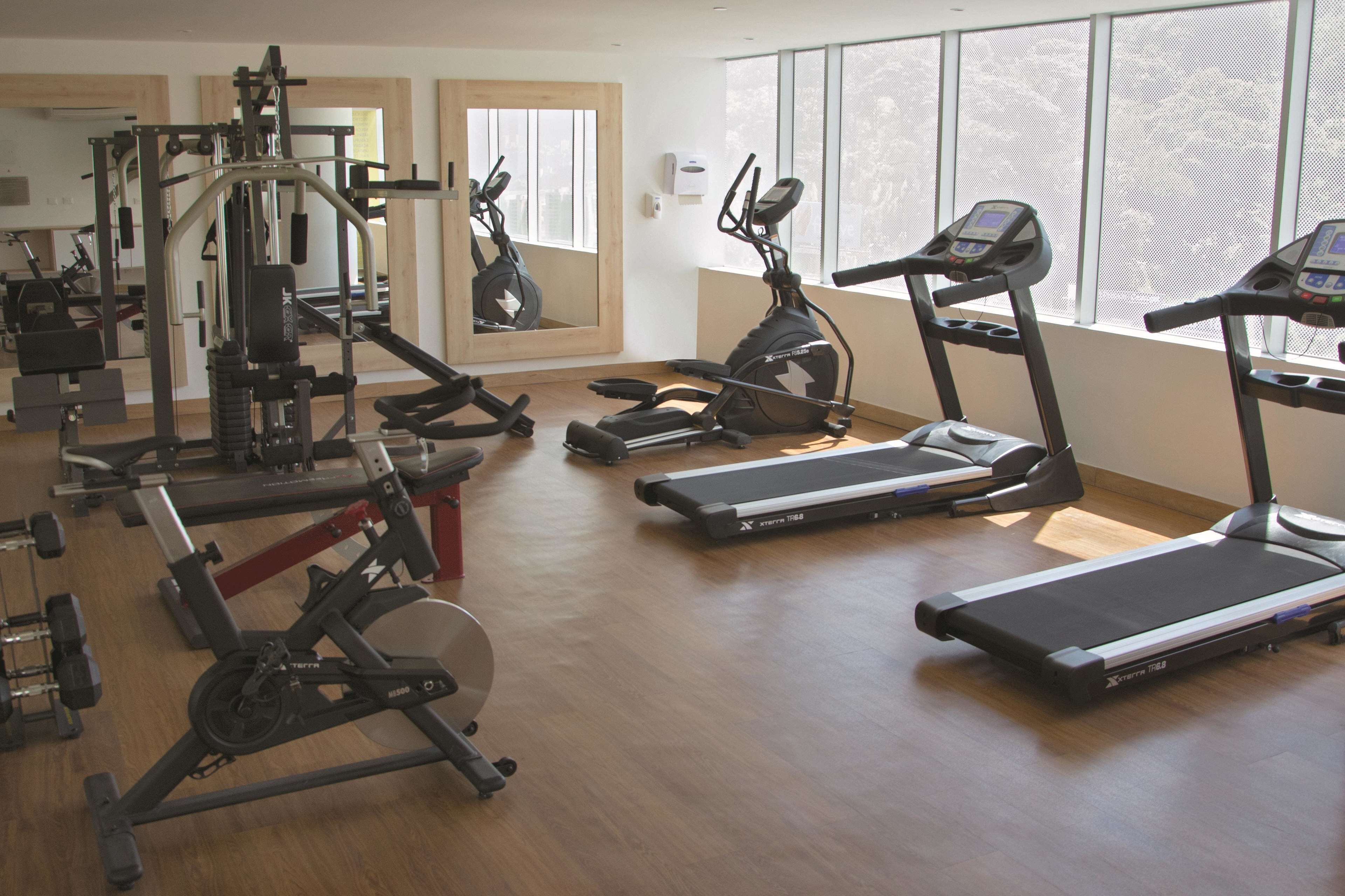 Un gimnasio con cintas de correr, bicicletas estáticas y máquinas de pesas.