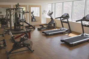 Un gimnasio con cintas de correr, bicicletas estáticas y máquinas de pesas.