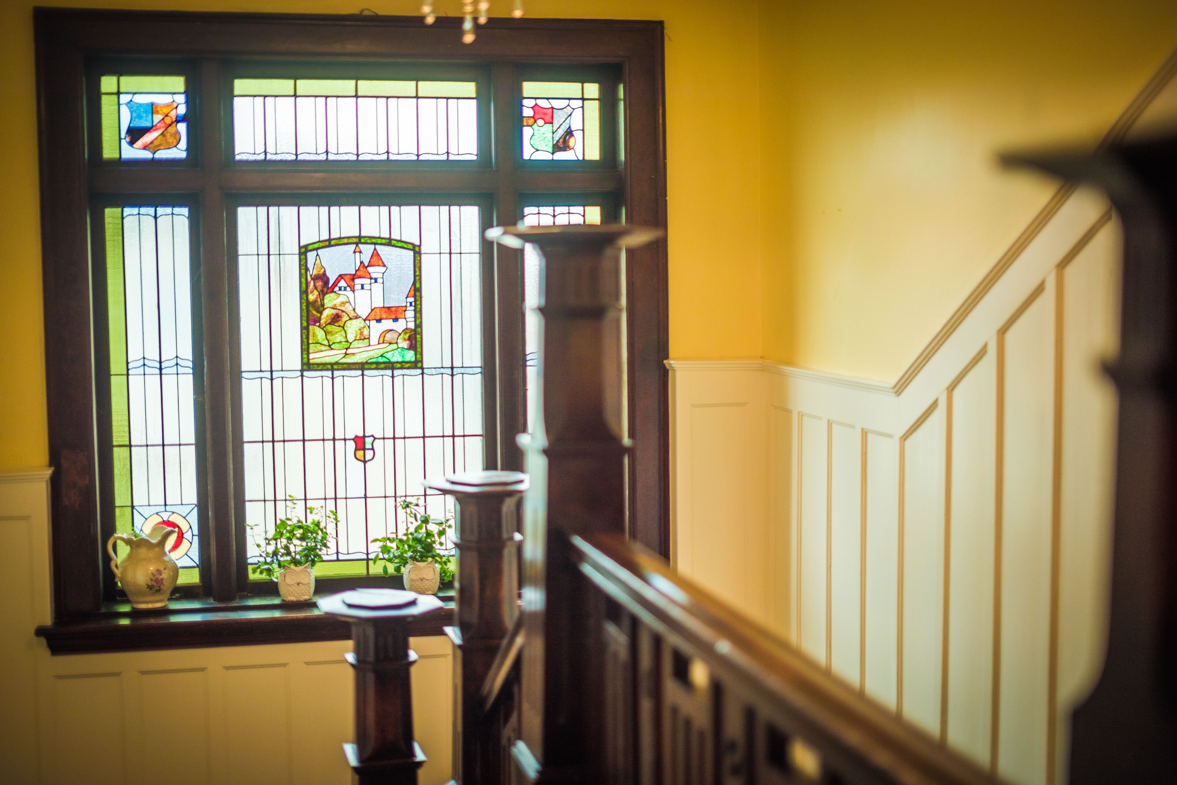 A staircase with a stained glass window featuring a landscape scene.