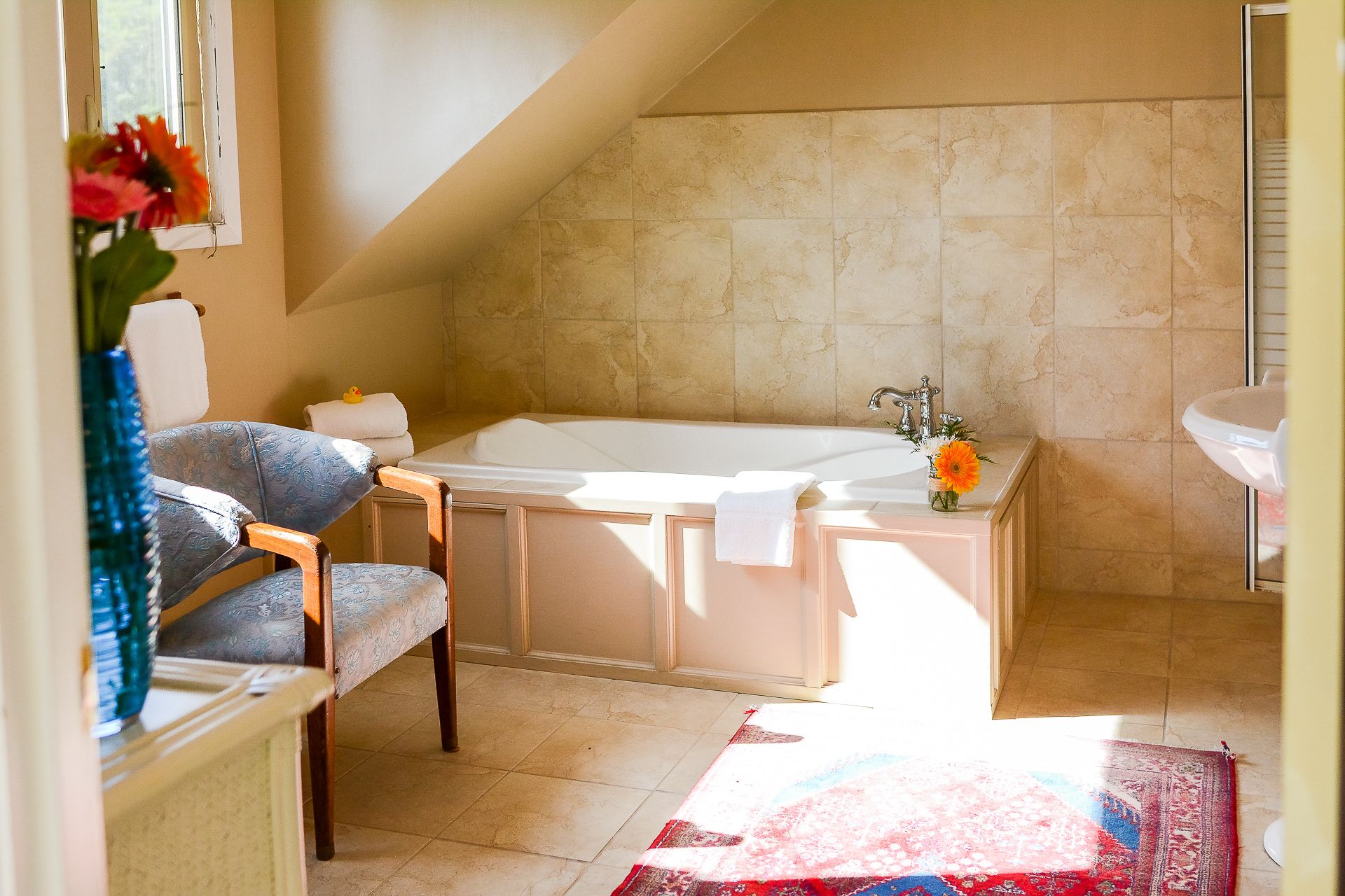 A bathroom with a bathtub, a sink, and a chair.