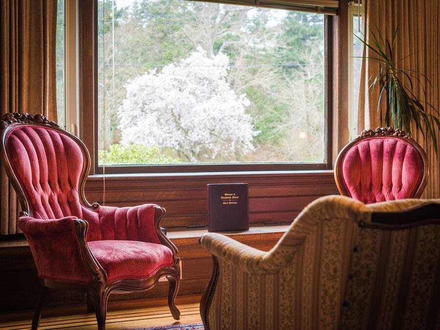Ein Zimmer mit zwei roten Polstersesseln und einem Buch mit dem Titel 'Welcome to the Estate'.