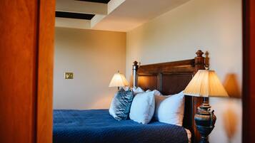 A bedroom with a wooden headboard, two bedside lamps, and a blue bedspread.