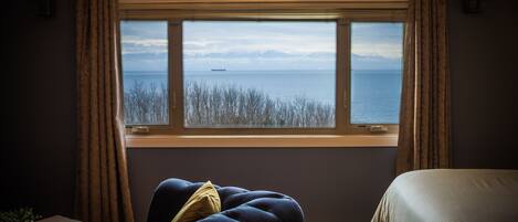 A room with a large window, a bed, a sofa, and a small table.