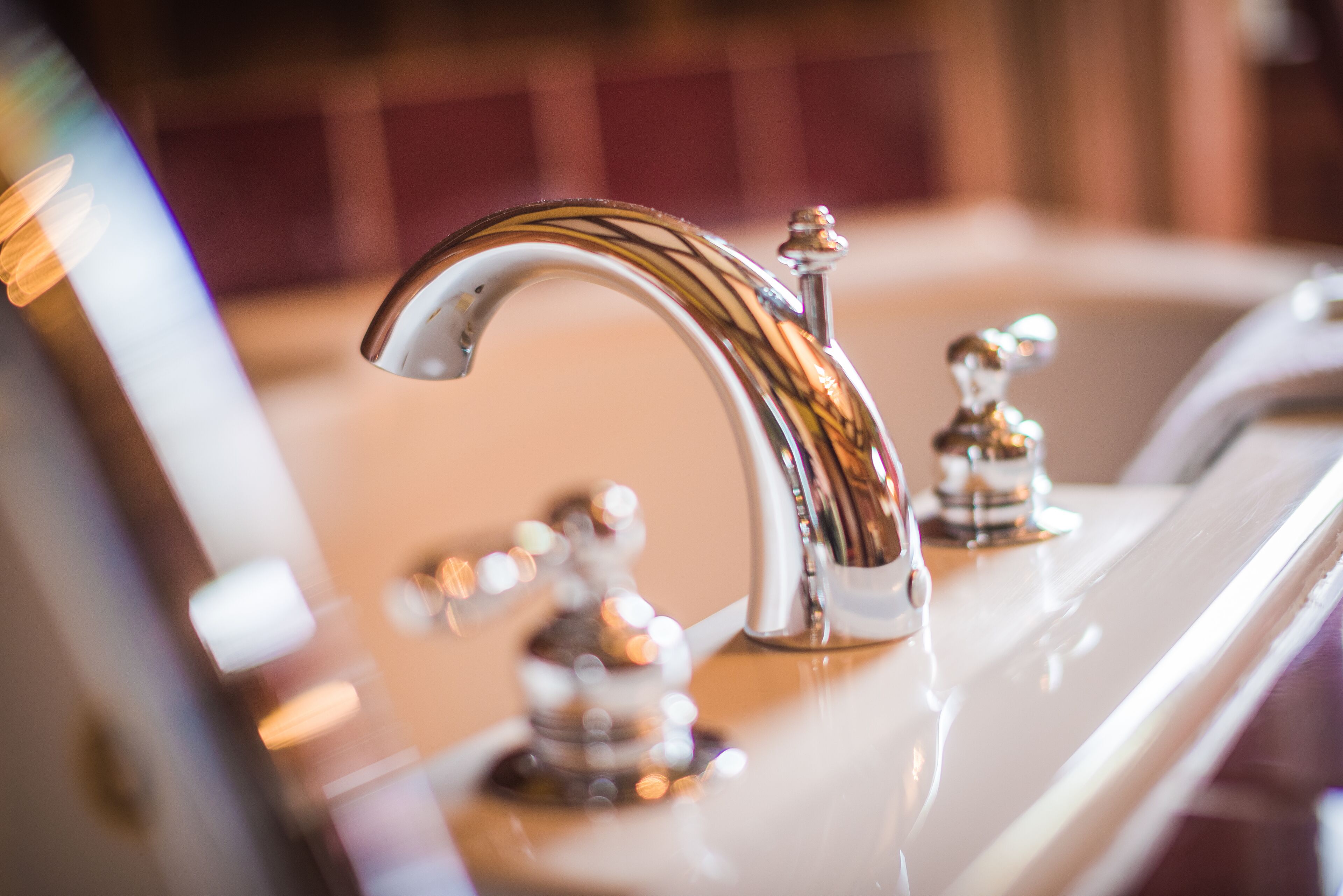 A bathroom with a chrome faucet and a mirror.