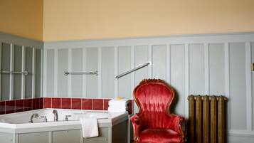 A bathroom with a bathtub, a red chair, and a radiator.