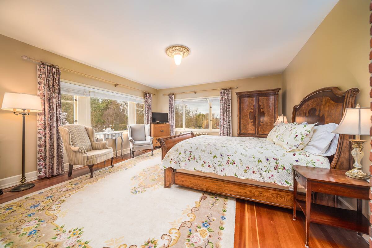 A bedroom with a large bed, a desk, a chair, and a wardrobe.