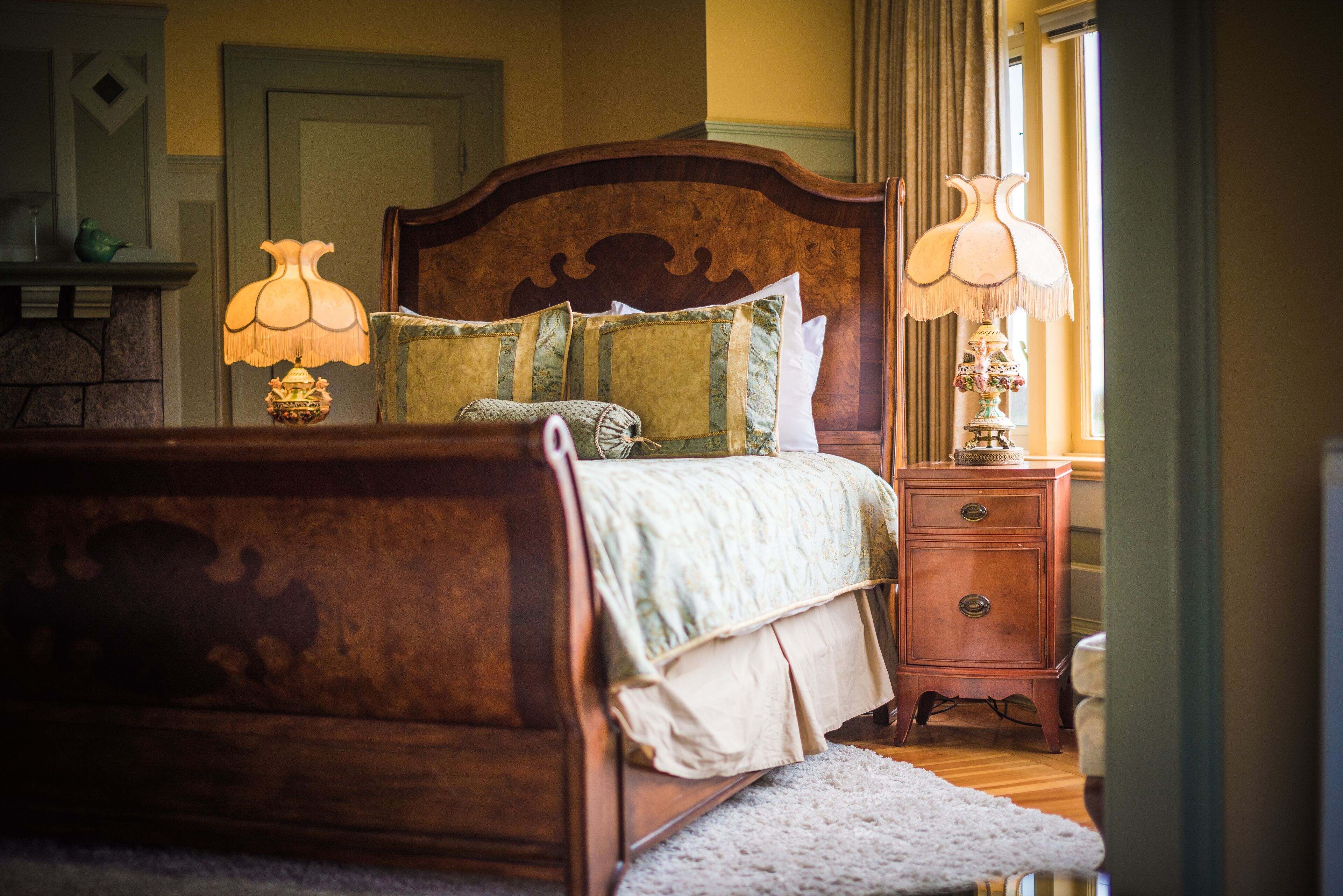 Una cama bien tendida con una cabecera de madera, dos lámparas de noche y una mesita de noche de madera con una lámpara.