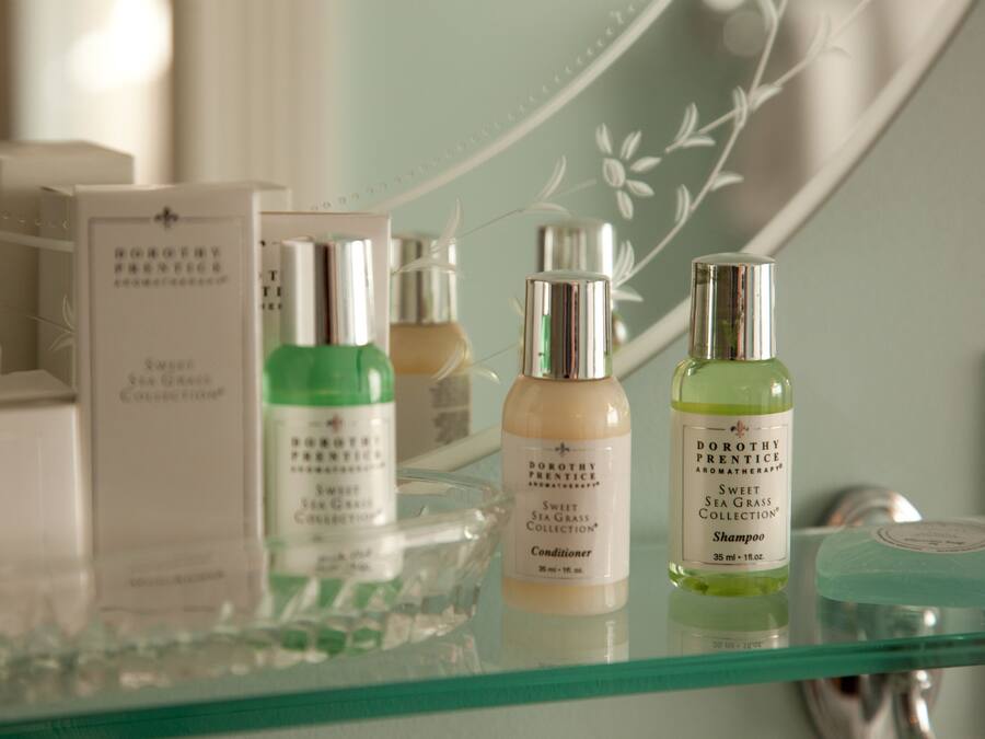 En hylla i glas med olika flaskor från Dorothy Prentices serie Sweet Sea Grass, inklusive balsam och schampo.