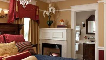 A hotel room with a bed, a fireplace, a mirror, and a window.