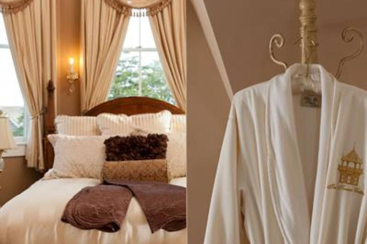 A neatly made bed with a brown throw blanket, a wooden headboard, and a hanging robe with a tag.