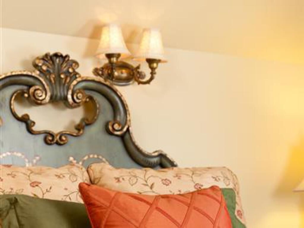 Una habitación con un aplique decorativo, un sofá estampado con motivos florales y un cojín verde.