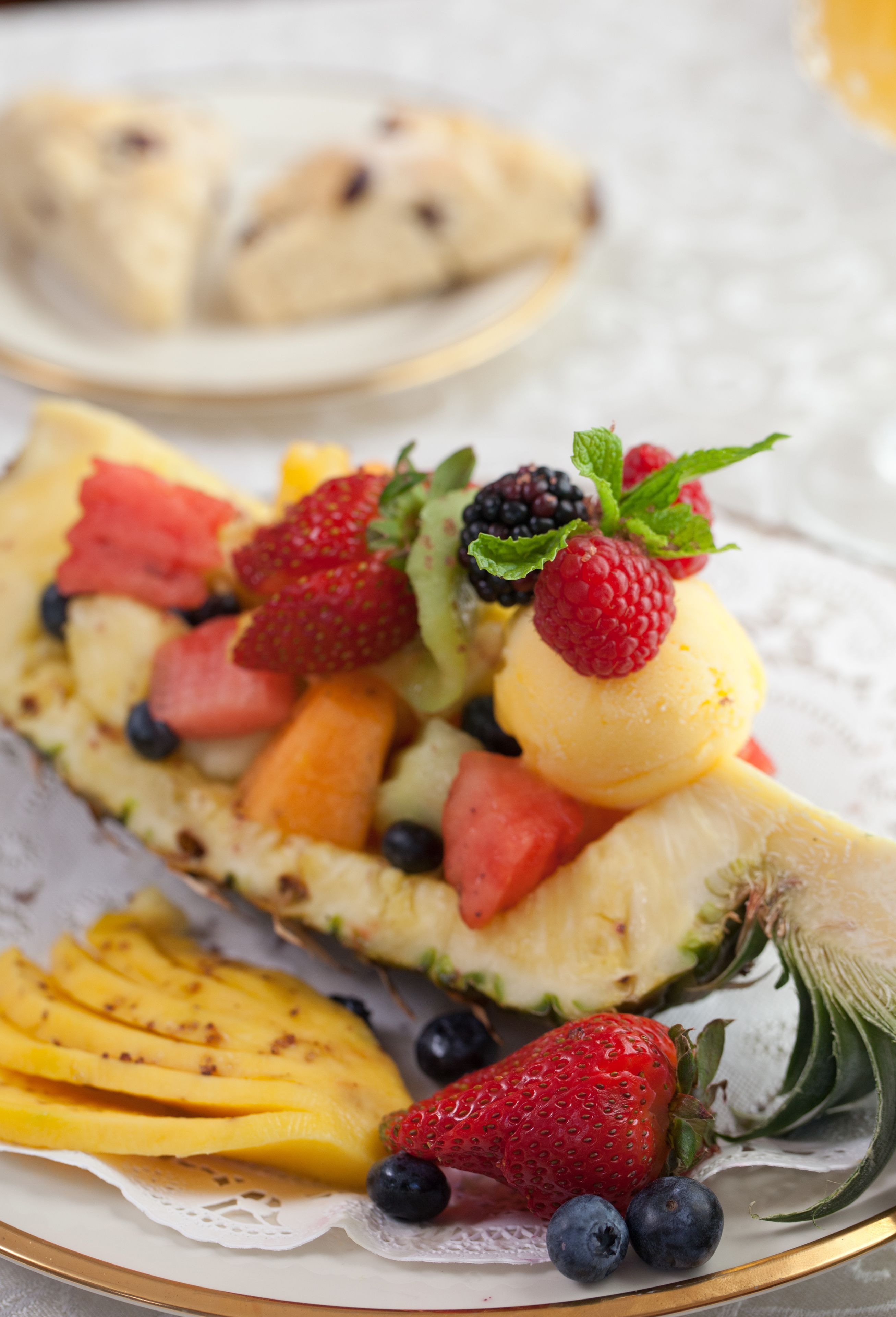 A dessert plate with a slice of cake topped with strawberries, blueberries, raspberries, and a scoop of ice cream.