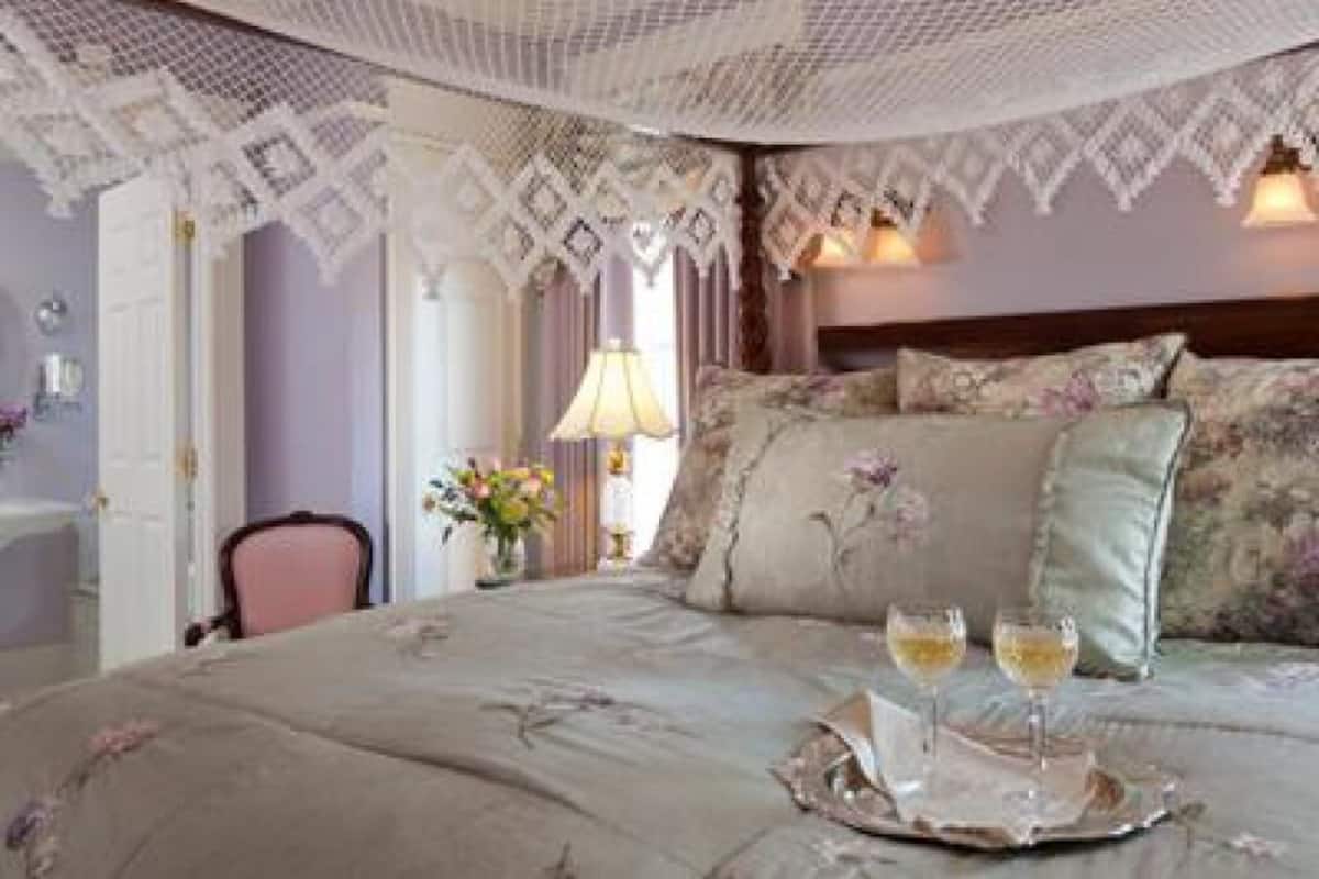 A bedroom with a bed, pillows, a tray with glasses, and a lamp.
