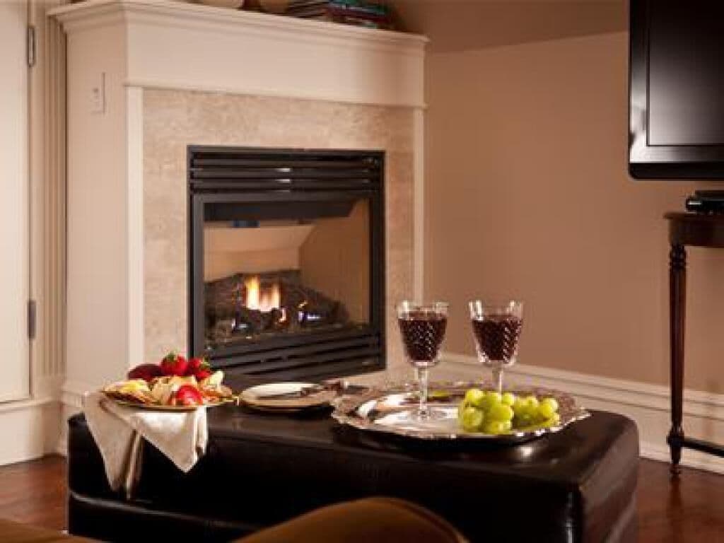 Una habitación acogedora con chimenea, una mesa de comedor con comida y bebidas, y un televisor en la pared.