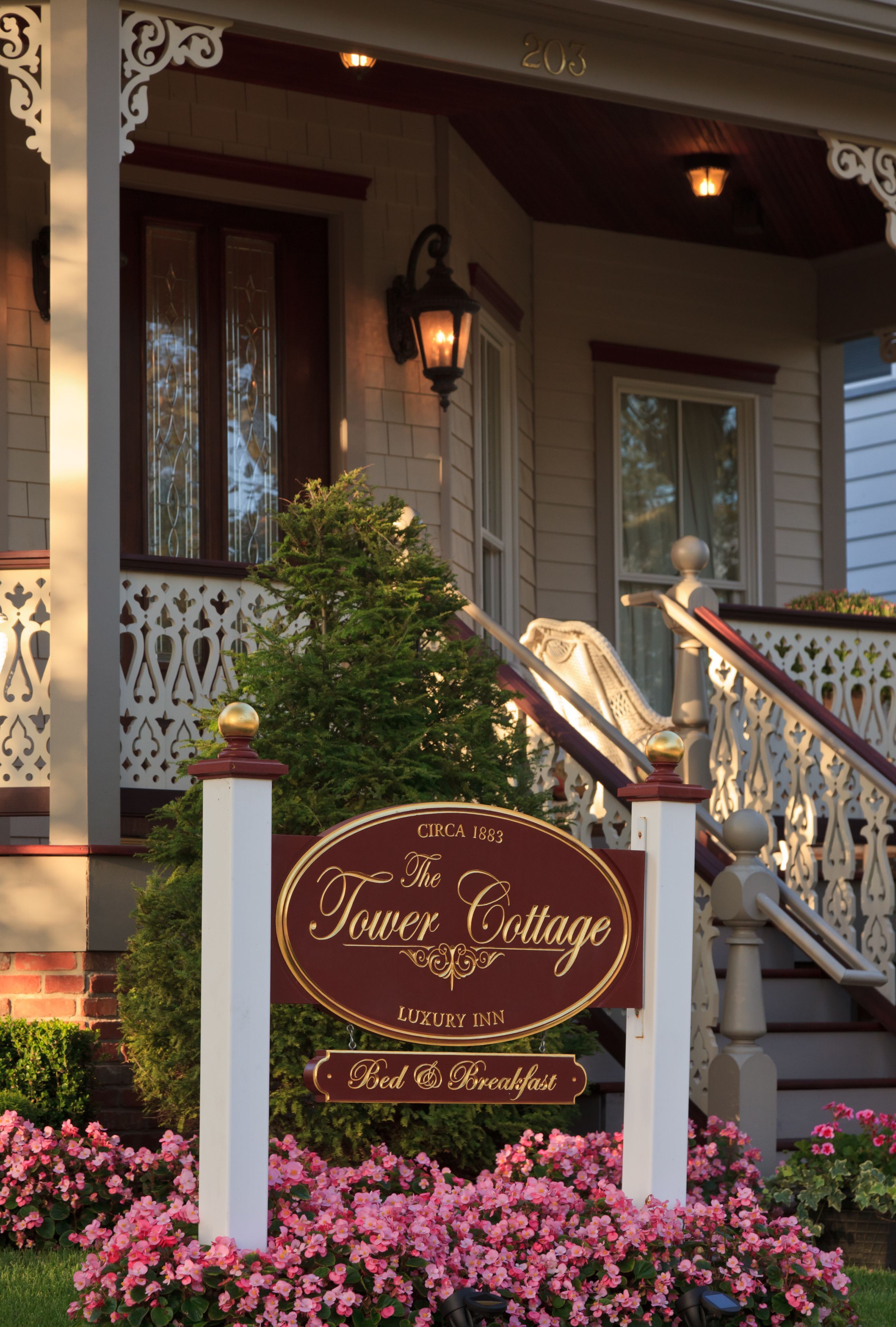 A sign for The Tower Cottage, a luxury inn with a bed and breakfast, featuring a classic architectural style with a porch and decorative railings.