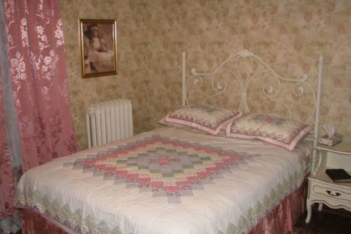 Une chambre à coucher avec un lit, une table de chevet, un radiateur et un tableau encadré au mur.