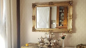 Un comedor con una mesa de madera, sillas y un espejo con marco dorado.