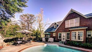 A brick house with a swimming pool, outdoor furniture, and a fenced backyard. - The Good House B&B (Natchitoches)
