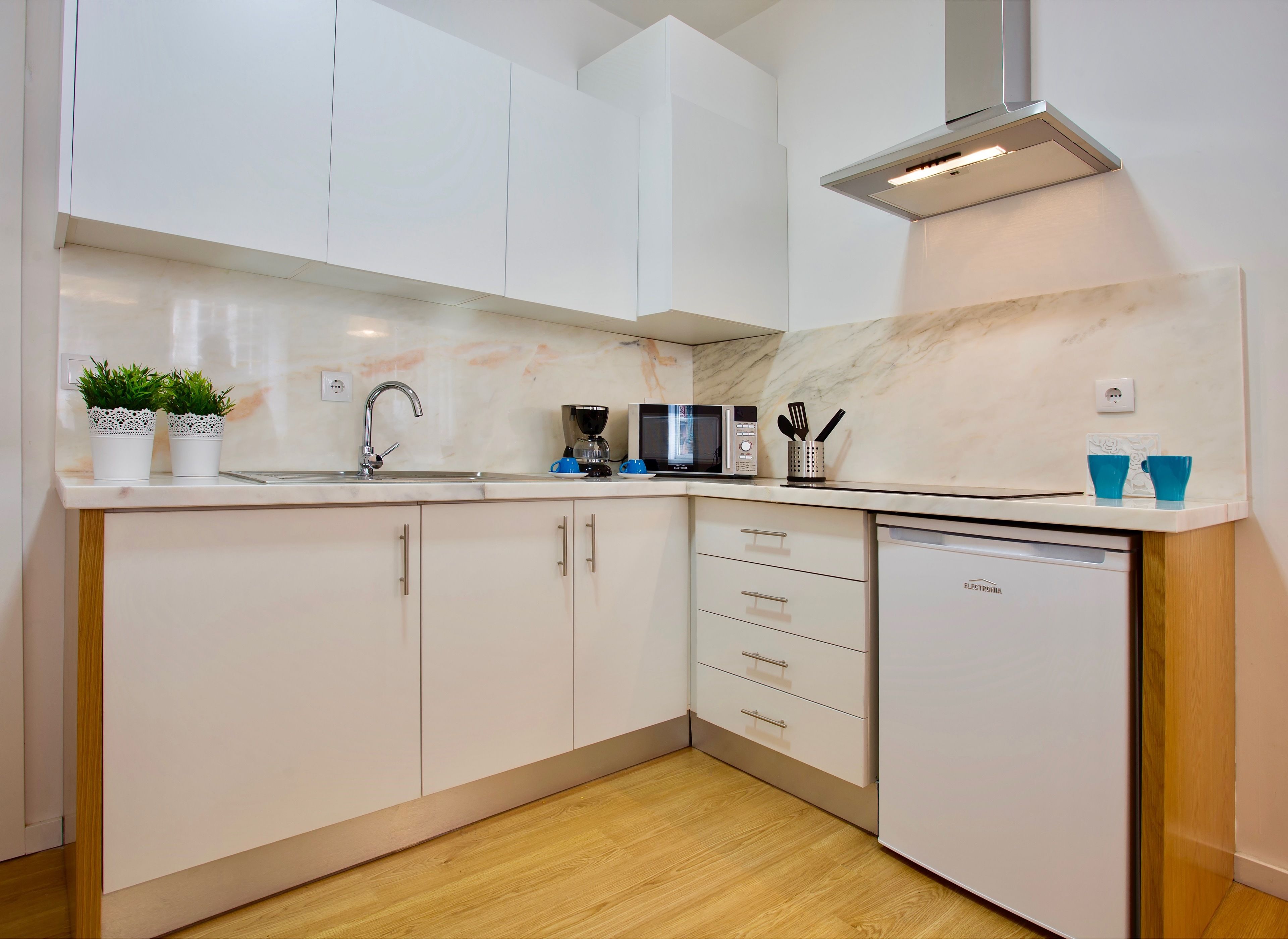A modern kitchen with white cabinets, a stainless steel sink, a microwave, and a dishwasher.