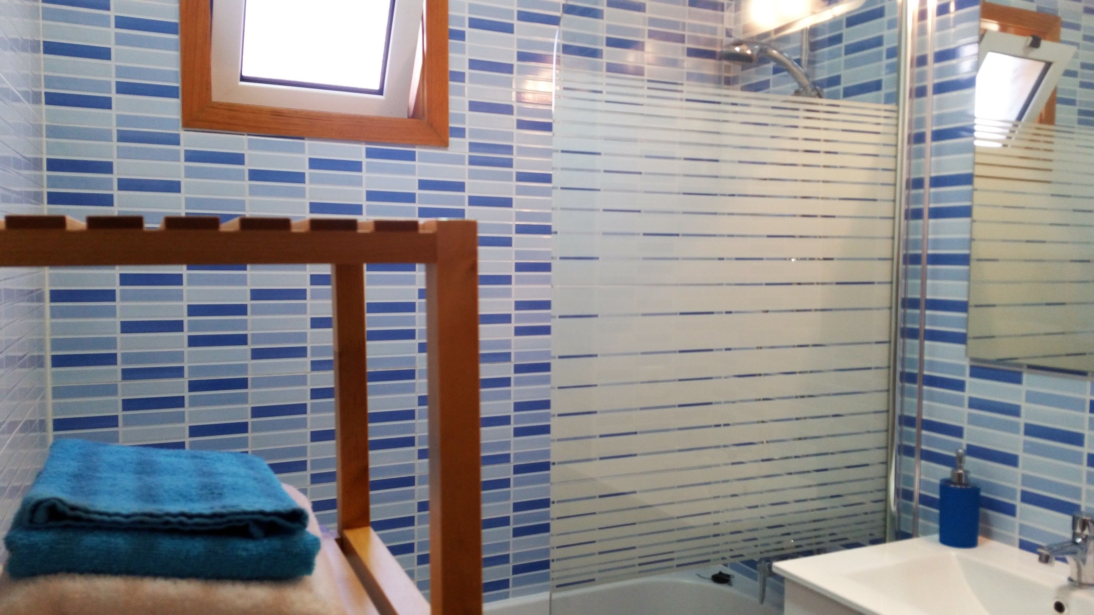 A bathroom with a shower, a sink, and a towel rack.