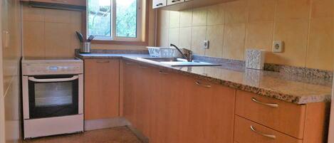 A kitchen with a built-in oven, a window, and a countertop with a sink.