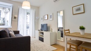 A modern living room with a sofa, TV, dining table, and chairs. - D&S - Porto São Bento Apartment II (Porto)