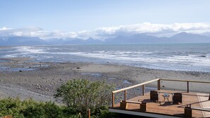 A wooden deck with two chairs and a table overlooking a rocky beach and ocean. - Homer Inn and Spa (Homer)
