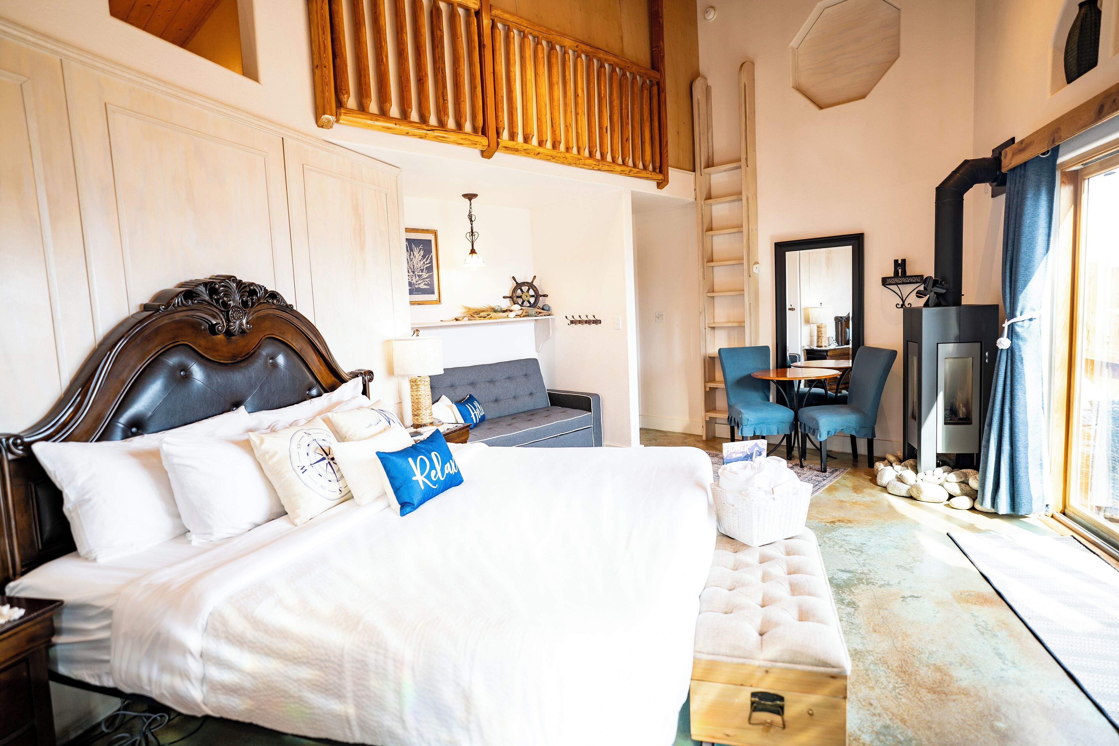 A bedroom with a large bed, a desk, a chair, and a fireplace.