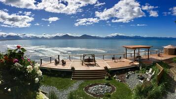 A wooden deck with outdoor seating, a gazebo, and a view of the sea and mountains.
