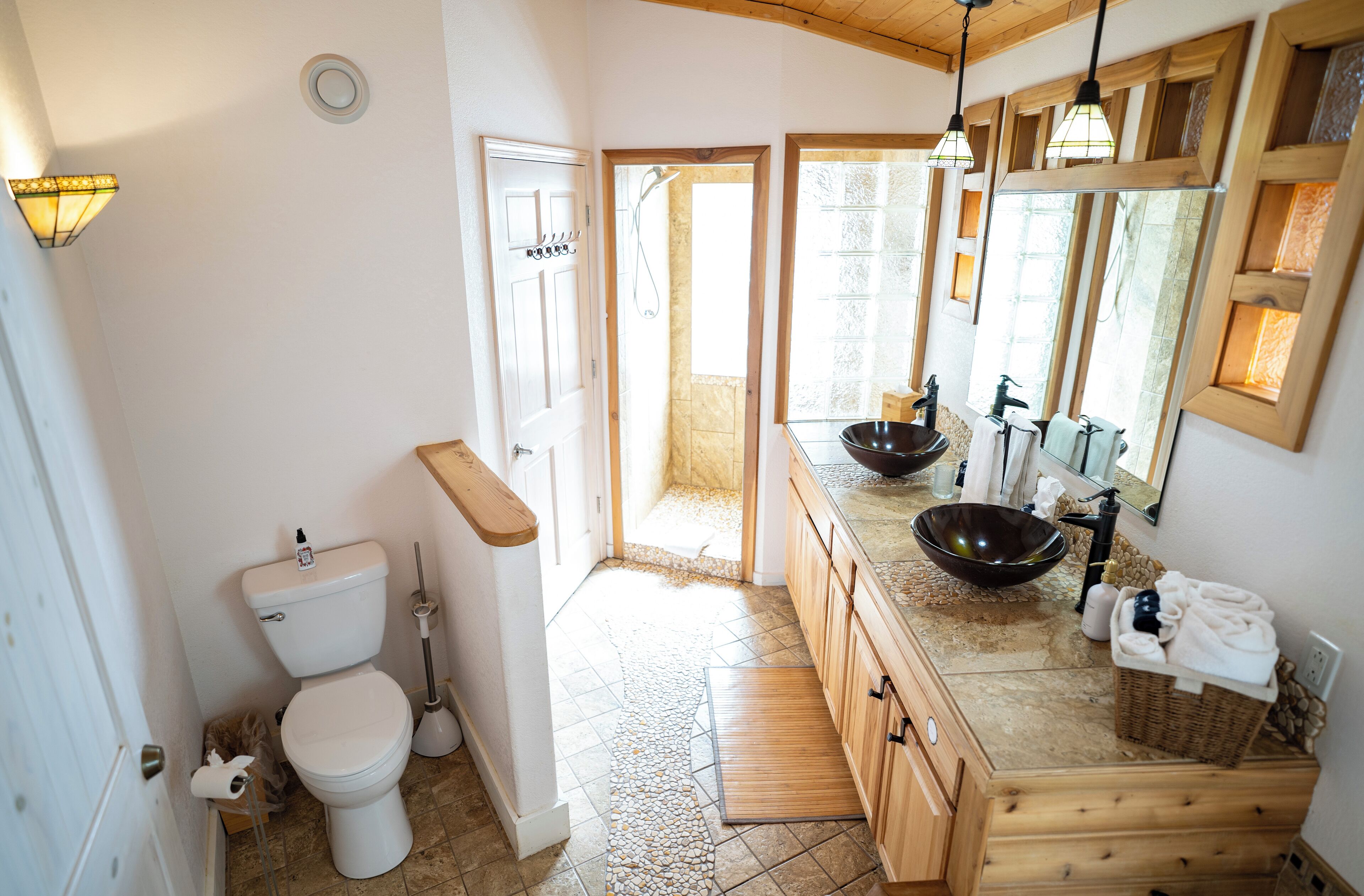 Ein Badezimmer mit Toilette, Bidet, Holzwaschtisch und einem großen Spiegel.