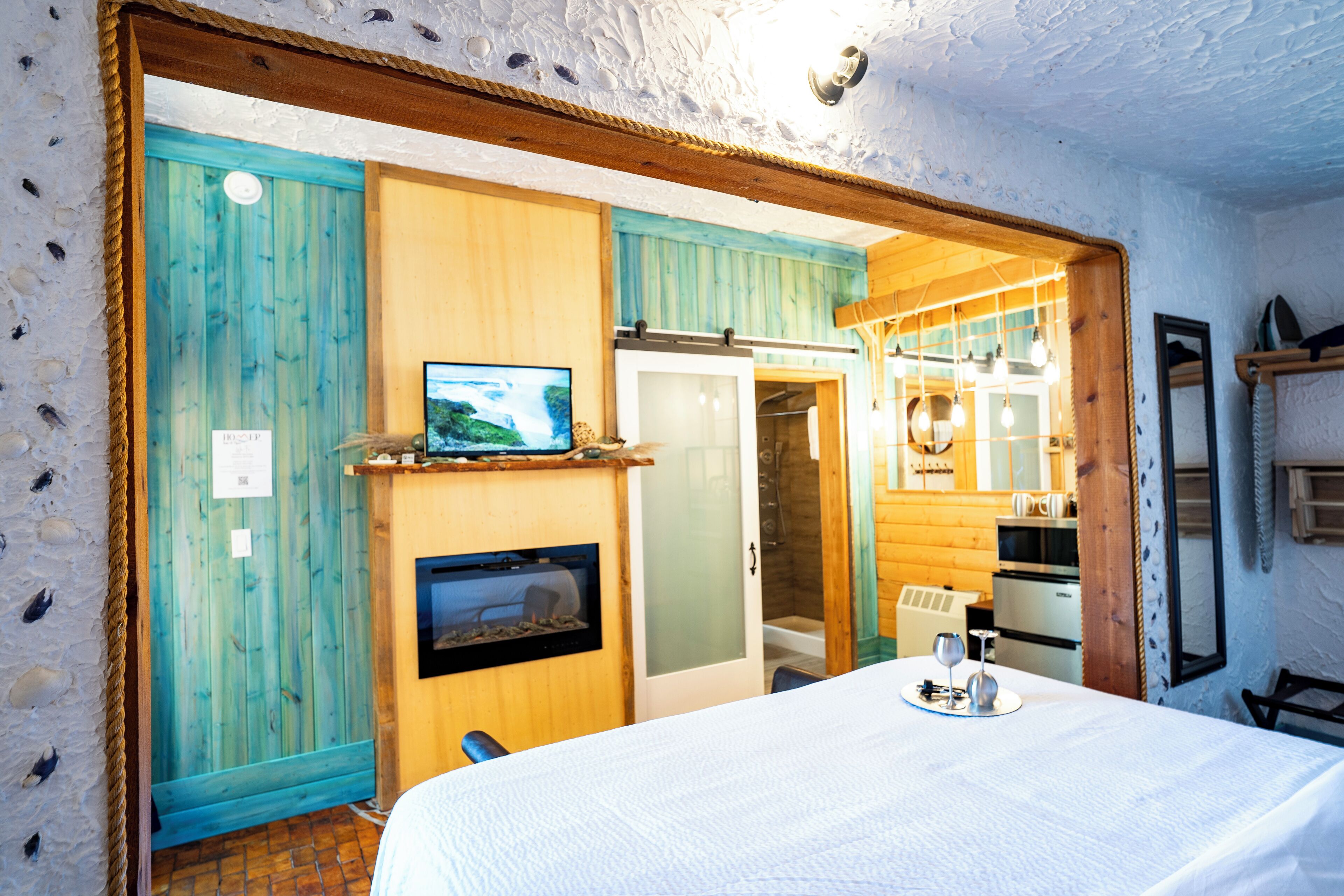A cozy room with a bed, a television, a fireplace, and wooden walls.