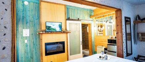 A cozy room with a bed, a television, a fireplace, and wooden walls.
