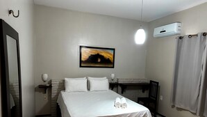 A hotel room with a bed, a painting on the wall, an air conditioning unit, and a curtain. - Pousada Alternativa (Aracati)