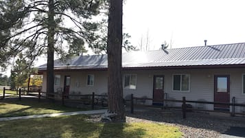 A single-story building with a metal roof, a front porch with benches, and a gravel driveway.
