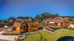 A cluster of wooden cabins with unique dome-shaped roofs, wooden decks, and outdoor seating areas. - Pichilemu Domos (Pichilemu)