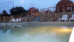 A swimming pool with lounge chairs and stone walls. - Pichilemu Domos (Pichilemu)