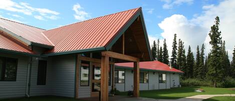 A modern house with a red roof, wooden porch, and a well-maintained lawn.