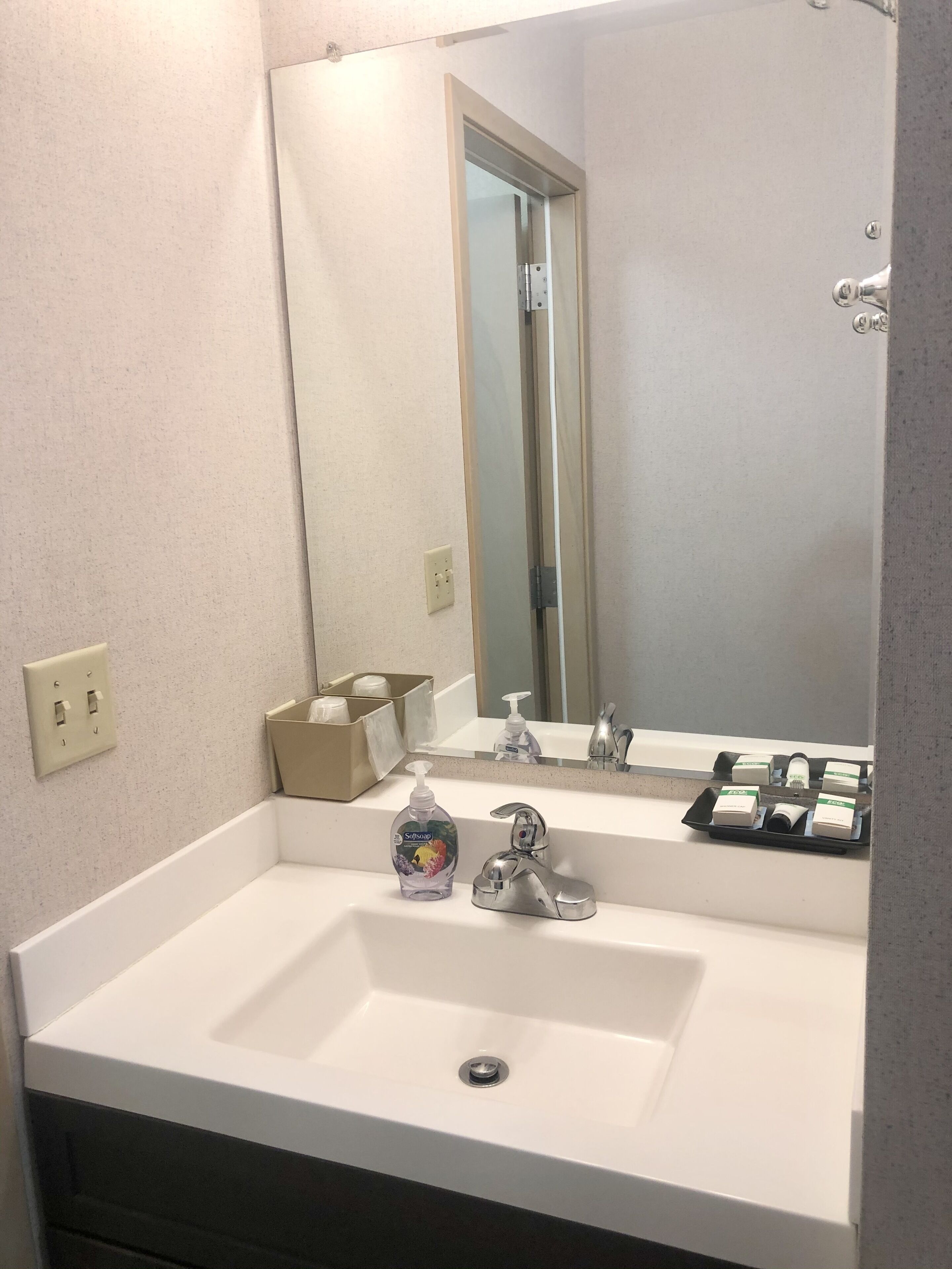 A bathroom with a white sink, a mirror, a faucet, and a soap dispenser.