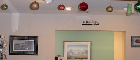 A reception area with a wooden ceiling, framed pictures, a desk, and Christmas stockings.