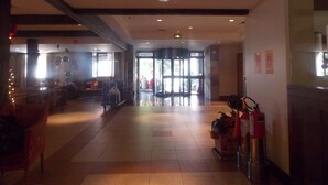 A spacious lobby with a tiled floor, a fire extinguisher, and a door leading to an outdoor area. - Raupp Flats Gramado 01 (Gramado)
