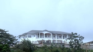 A large, multi-story white building with a flat roof and multiple balconies.