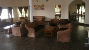 A spacious room with wicker furniture, a large window, and a painting on the wall.