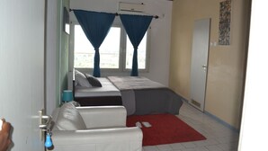 A bedroom with a bed, a red rug, a white sofa, and a door.