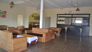 A spacious room with wicker furniture, a bar area, and a large window.