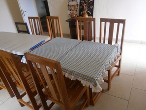 A dining table with a checkered tablecloth, surrounded by wooden chairs. - The LK Hotel (Bonadikombo)