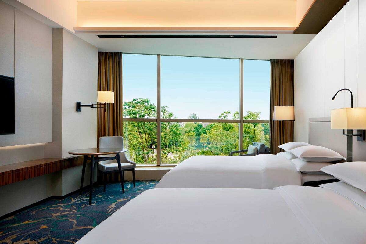 Een hotelkamer met twee bedden, een tafeltje, een stoel en een televisie.