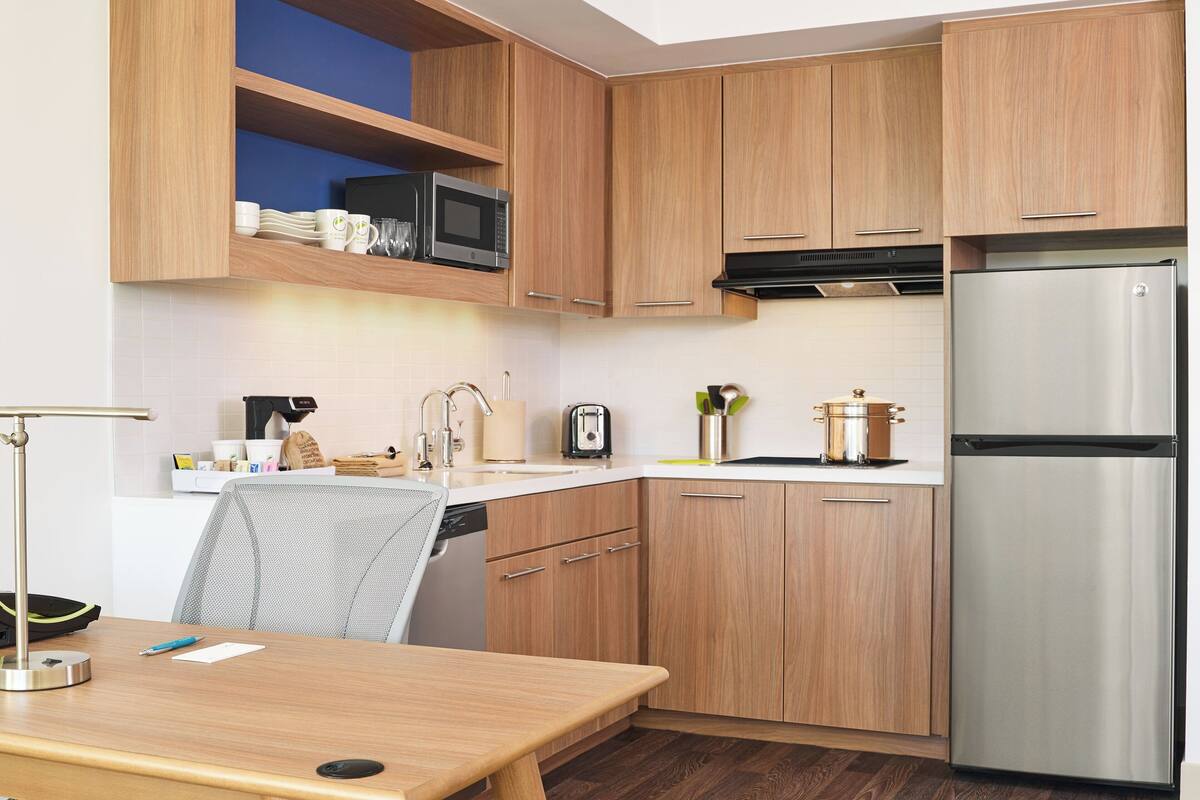 Een moderne keuken met houten kastjes, een roestvrijstalen koelkast, een magnetron en een spoelbak.
